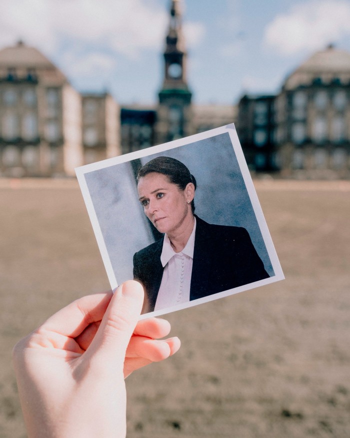A woman’s hand holding a Polaroid of Birgitte Nyborg, with Christiansborg Palace in the distance behind it 