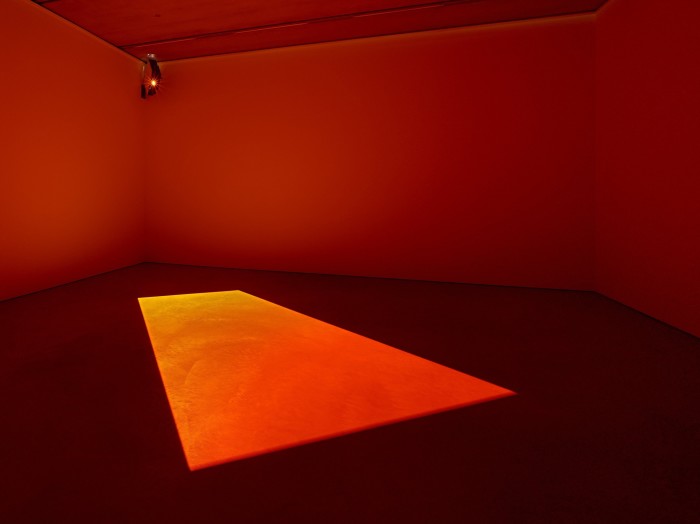 A room filled with orange light; a brighter orange rectangle is cast on the floor