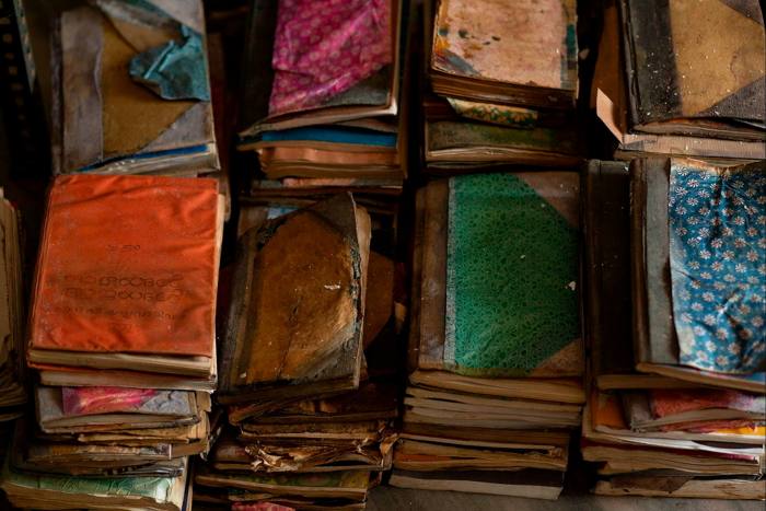 Piles of old, dirty books with torn marbled covers