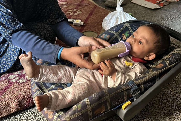 A mother feeds her seven-month-old baby a bottle of lentil soup in Gaza