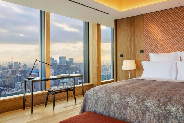 An orange- and  saffron-themed guest room, with a golden bedspread, overlooking the city