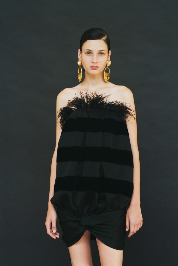 The little black dress is not so basic. Eléonore wears Saint Laurent by Anthony Vaccarello velvet stripe and feather dress, £1,750. Schiaparelli brass Padlock earrings, £800