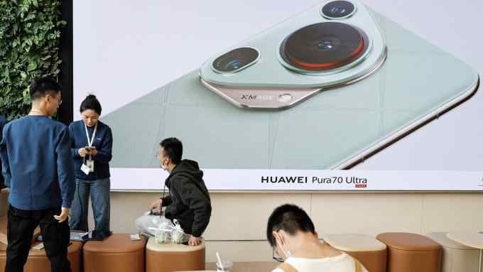 People sit near a screen showing new Huawei Pura 70 series smartphone