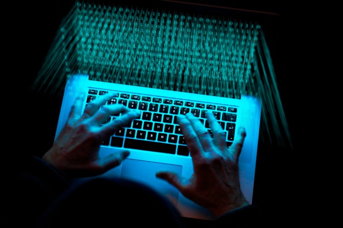 A pair of hands using a laptop in a dimly lit environment