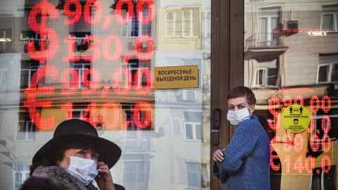 People walk past a currency exchange office in Russia