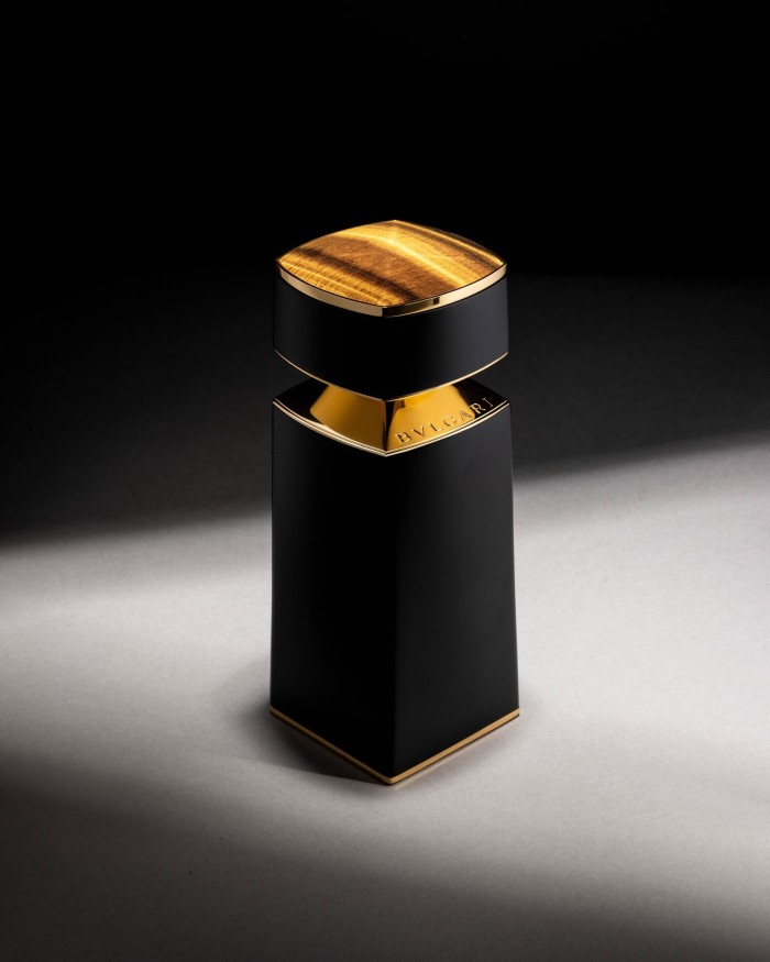 A sleek, rectangular, black bottle of BVLGARI perfume, accented with a gold cap and a matching gold label around the neck