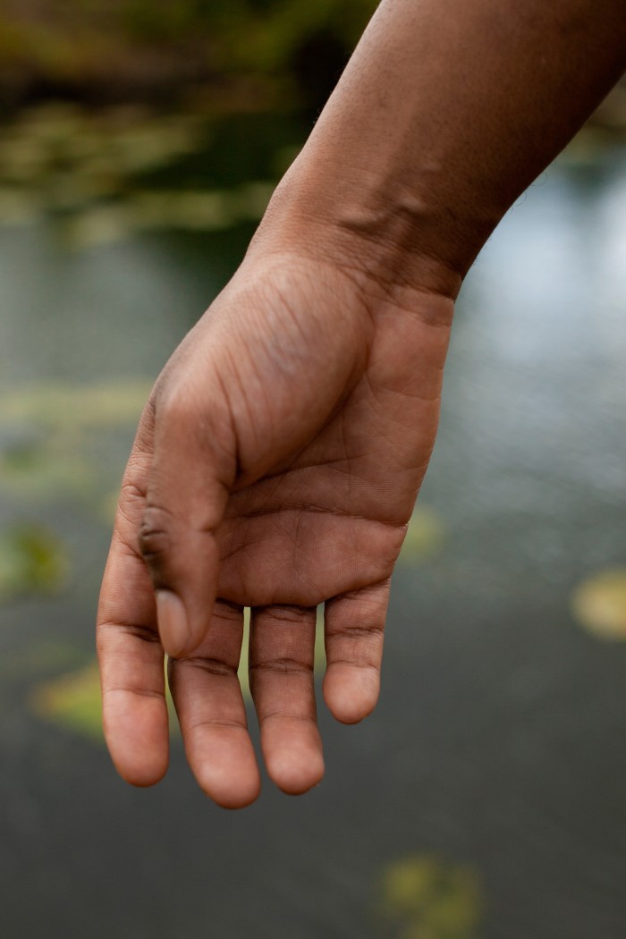 A close-up of Runako Nyauchi’s hand against the water of the pond