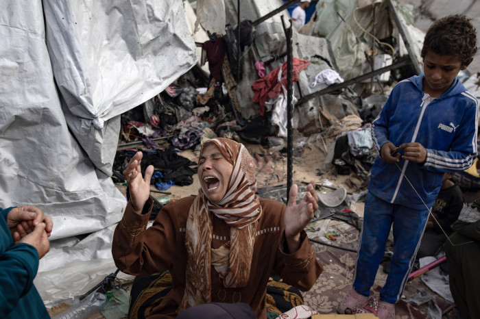 A woman reacts as Palestinians inspect tents after an Israeli army operation on an area in Rafah
