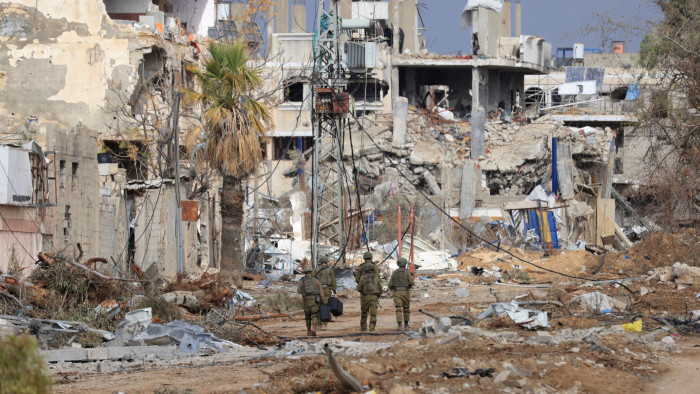 Israeli troops walk past destroyed buildings on the outskirts of Gaza City