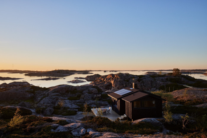 Wooden cabin on rocky island at dusk