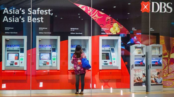 A woman uses an ATM outside a DBS bank in the central business district of Singapore