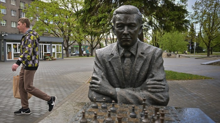 A statue of Paul Keres sitting at a chess board, while a man walks by in the background