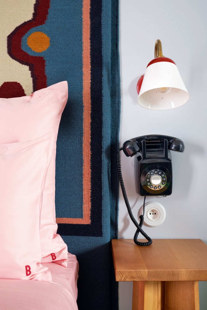 Tapestry and an antique-style telephone on a bedroom wall at Hôtel de la Boétie