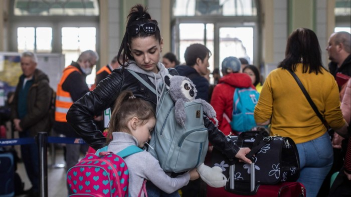 A woman and child from Ukraine wait in a ticket hall at a Polish railway station