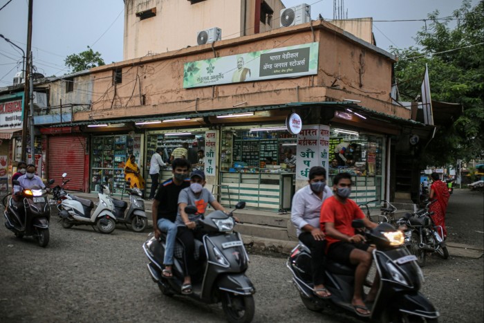 people on motorcycles drives past a medical store