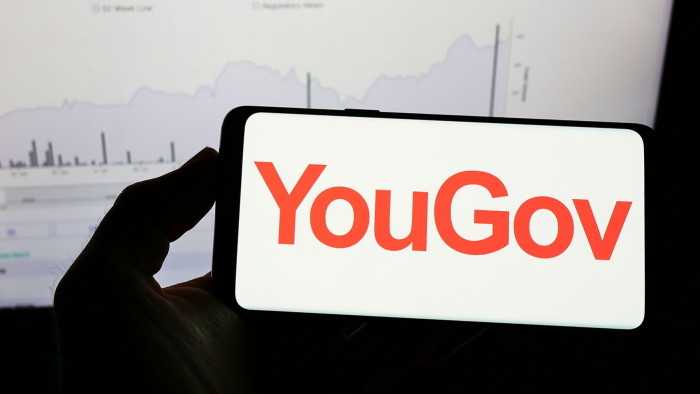Person holding mobile phone with logo of British market research company YouGov