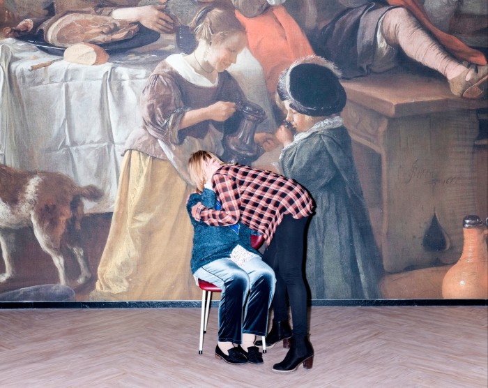 A woman hugs her mother who is seated in front of a mural