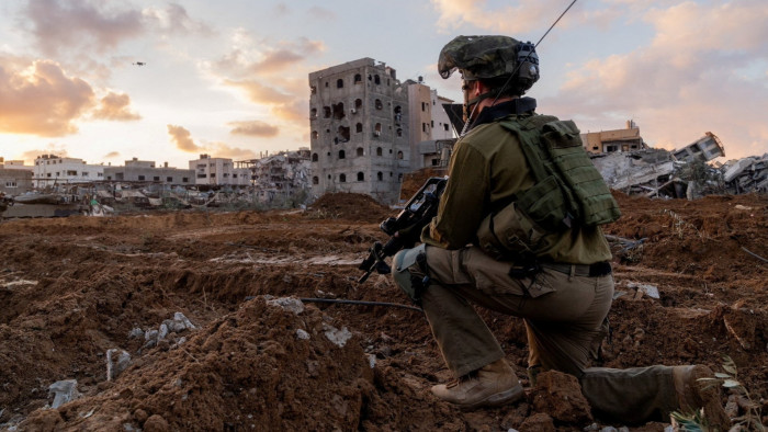 An Israeli soldier in front of bombed buildings