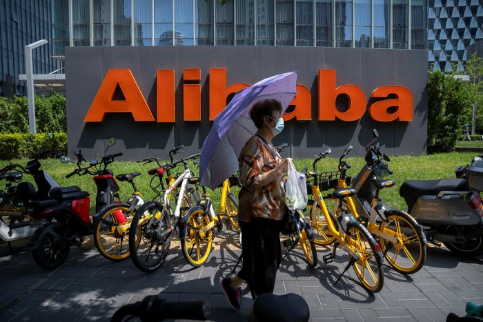 A woman holds an umbrella as she walks past the offices of Chinese ecommerce group Alibaba in Beijing