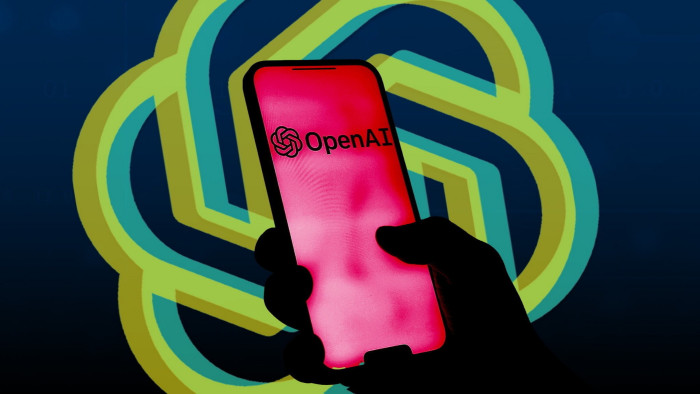 OpenAI logo behind a hand holding a smartphone