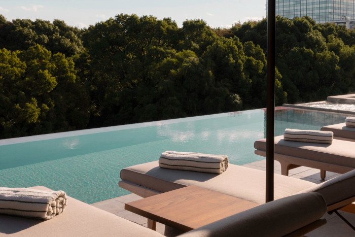 Daybeds by the infinity pool, with treetops in the background