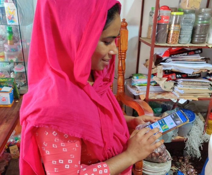 A shopkeeper in Bangladesh holds a smartphone with the ShopUp app