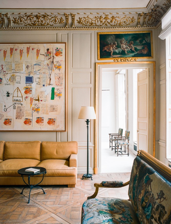 A bespoke sofa by Festen, Louis XVI canapé salon (on right), neoclassical side table and 1930s bronze floor lamp. On the wall hangs Icarus Esso, 1986, by Jean-Michel Basquiat