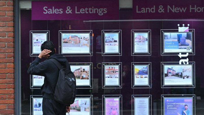 A member of the public looks at houses for sale in the window of an Estate Agents in Reading, west of London
