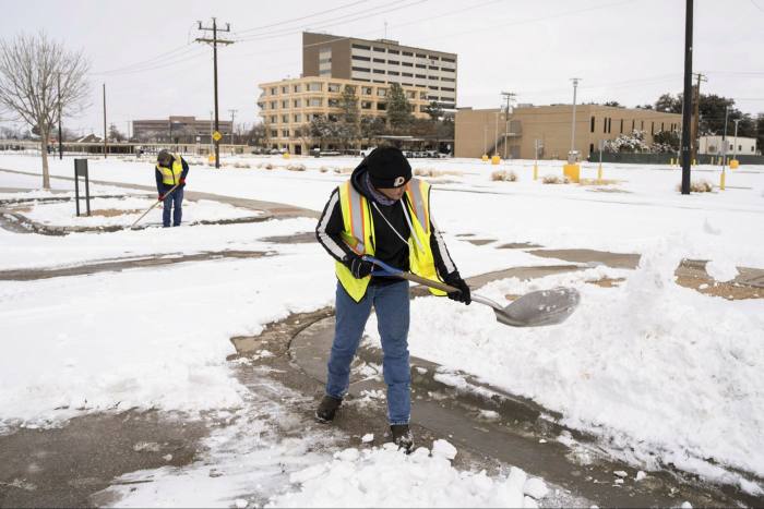Workers clear snow from a parking lot in Midland, Texas, in February. . .