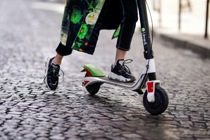 PARIS, FRANCE - SEPTEMBER 29:  Caroline Daur wears a green printed coat, sneakers, sunglasses, a Prada bag, and is using a Lime-S electric scooter from the bike sharing service company ‘Lime’,