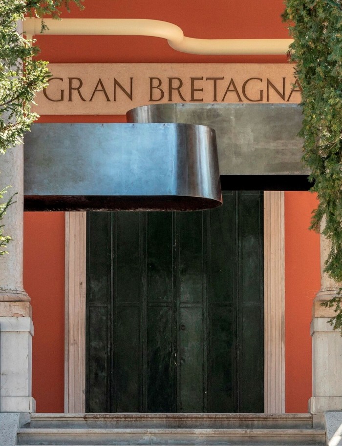 Black metal shapes installed over the door of a building marked ‘Gran Bretagna’