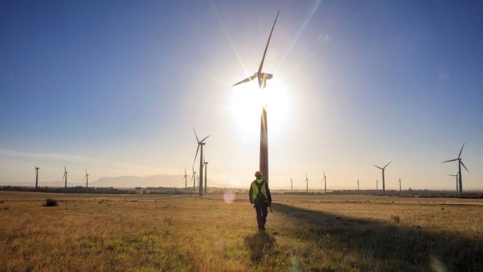 A worker in front of a number of wind turbines in a field