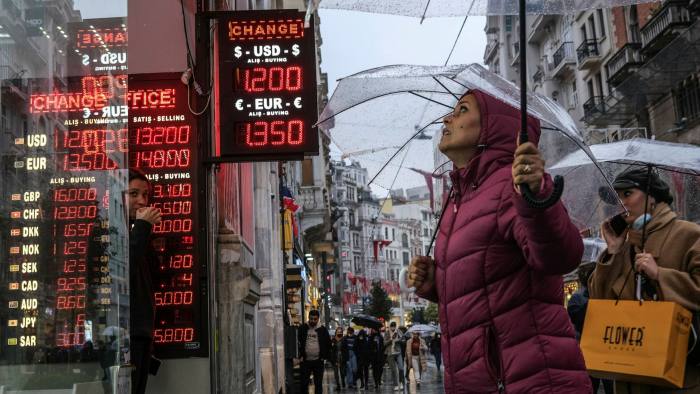 People check rates on a board of currency exchange office in Istanbul, Turkey