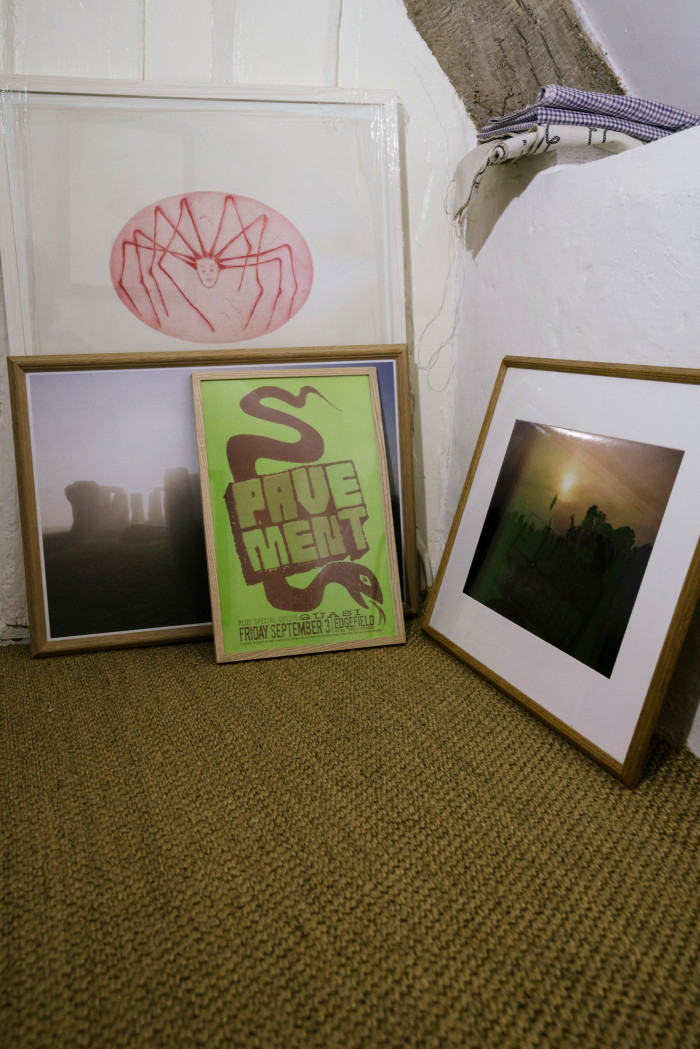 Framed artworks awaiting hanging: Louise Bourgeois’s Spider Woman, Tom Beard’s photograph of Glastonbury Stone Circle at dawn, a poster-flyer for Pavement and a Jeremy Deller photograph of Stonehenge