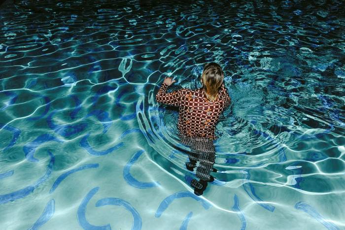 A person wades into the pool, which has blue painted curves on the bottom