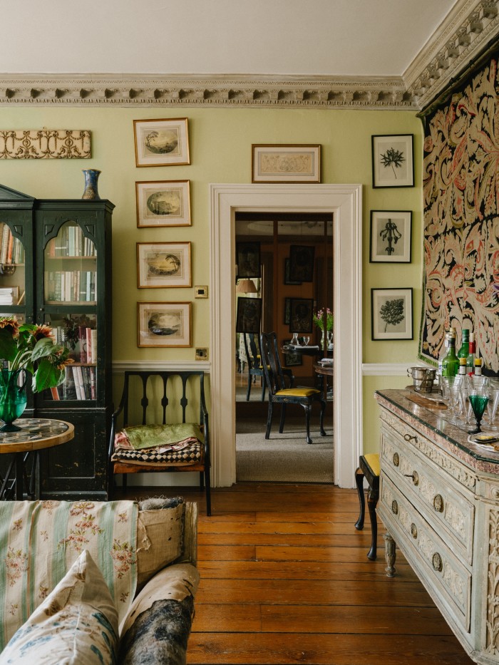 The drawing room with its bookcase that belonged to Min Hogg, 19th-century French needlepoint on the wall and c1780 Piedmontese commode used as a bar