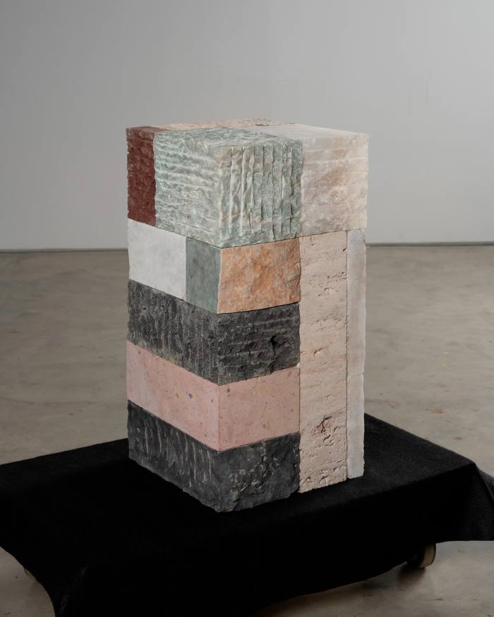 A cuboid sculpture composed of bricks of different materials