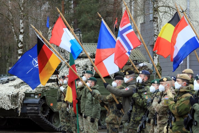 Nato troops in Lithuania hold the national flags of alliance members