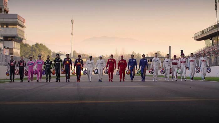 twenty F1 drivers standing side-by-side on a racetrack