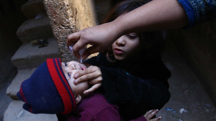 A health worker administers polio vaccine to a child in Karachi, Pakistan