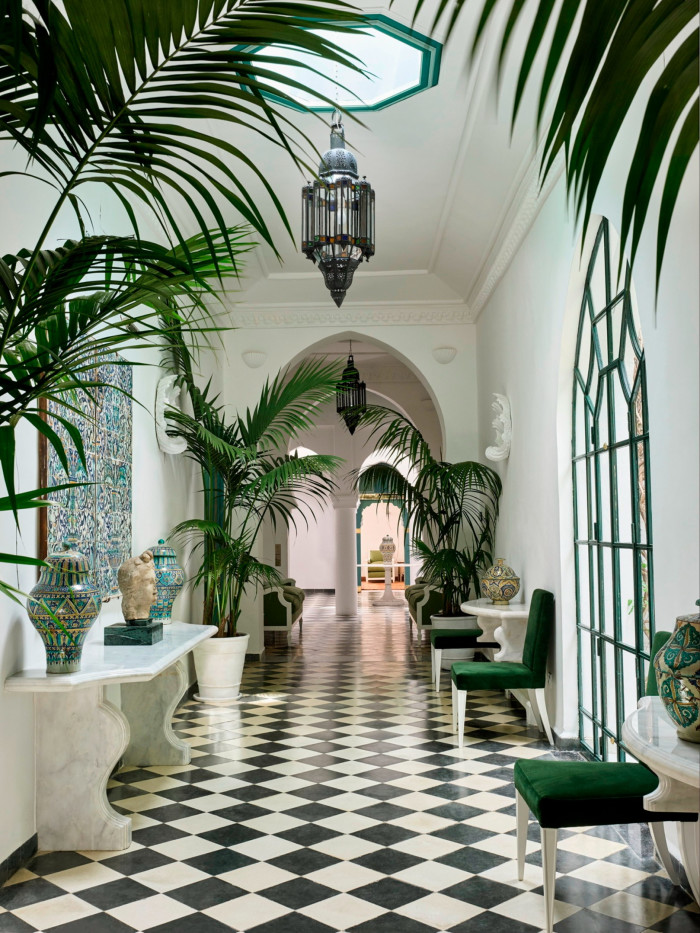 hotel foyer with luxuriant plants, black and white tiled floor, vast arched windows