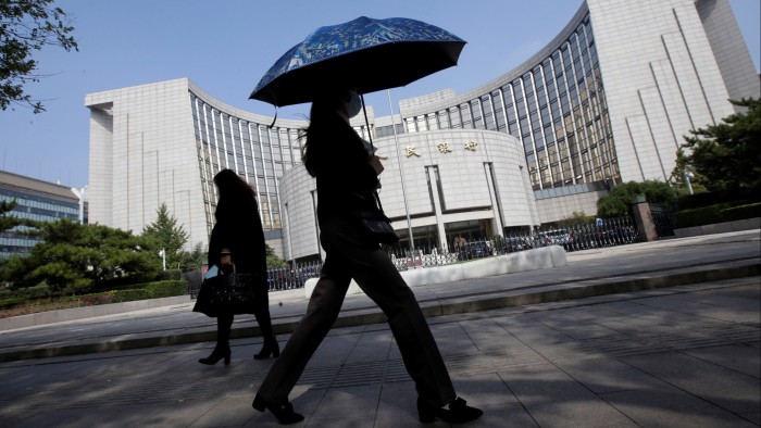 People walk past the headquarters of the People’s Bank of China (PBOC), the central bank, in Beijing