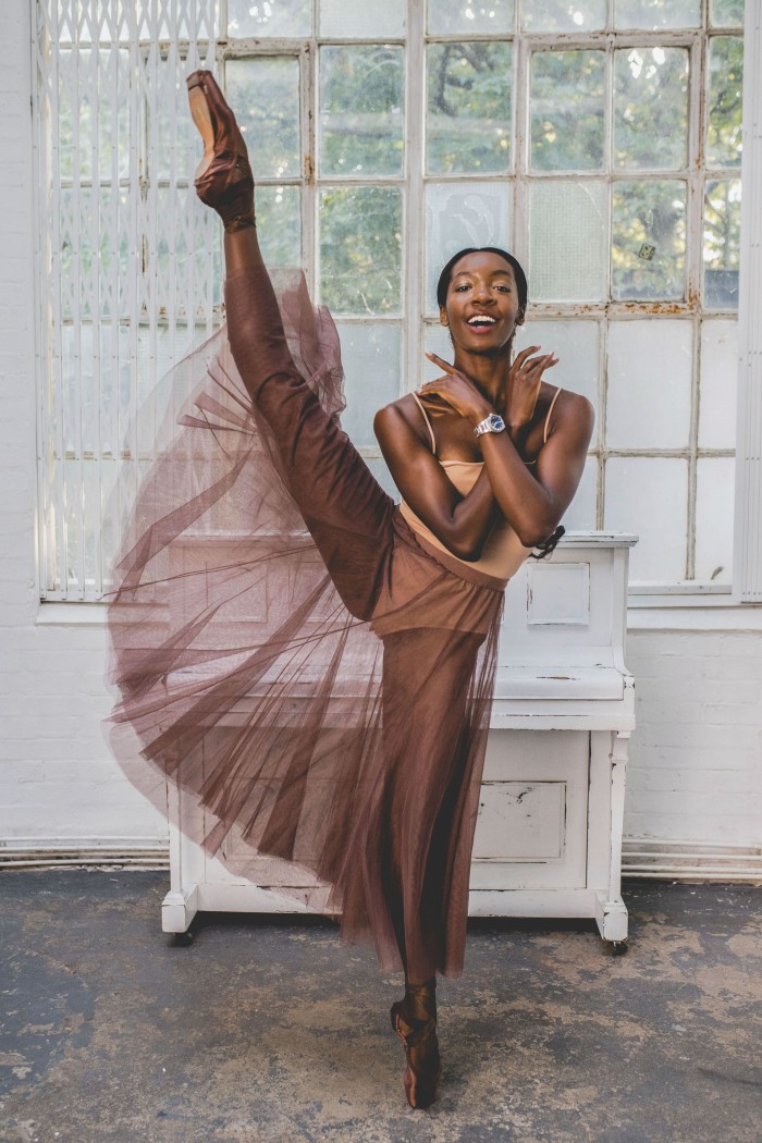 Ballet dancer Precious Adams standing on her left leg, right leg up in the air, and wearing a wristwatch 