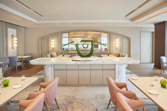 The cream, pale-pink and beige-hued dining space at the hotel’s Sézanne resturant, with a large ceramic counter in the centre and a large arched mirror on the back wall