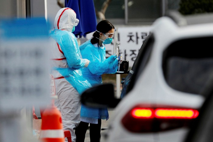 A motorist is checked for coronavirus at a drive-through site in Daegu. When workers fell ill at a logistics centre, the Korean Centers for Disease Control and Prevention was able to identify and test 5,000 people within three days