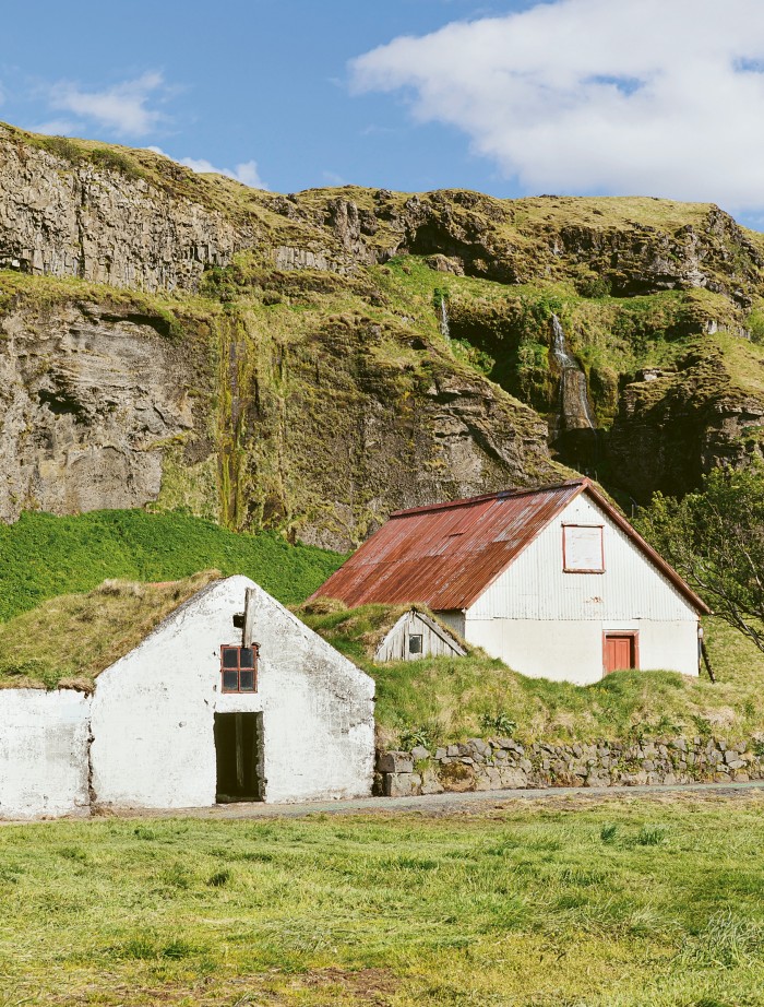 Small houses in a rural setting beneath a cliff in Iceland