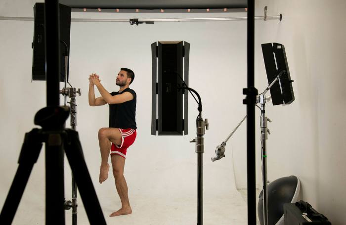 Photo of a man lifting a leg in a yoga-like pose in a photographic studio