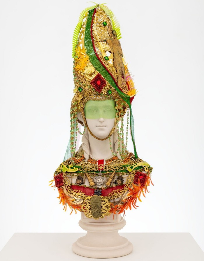 Bust of a dignified younger woman covered in a cap and neck piece made from bright sequins and thread and feathers