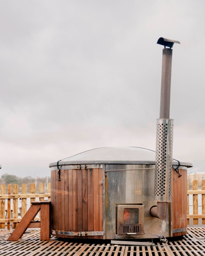A wooden stove with a thin tiny chimney on decking at CopenHot sauna complex