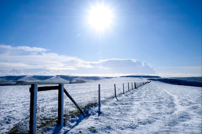 The sun shining over a snowy Mount Caburn on the South Downs in East Sussex